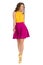 Cute Smiling Walking Woman In Vibrant High Heels, Pink Mini Skirt And YellowTop. Front View