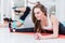 Cute smiling young lady in sportswear doing advanced middle split exercise bending over leaning on arms in gym