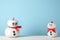 Cute snowmans with red bow against blue background