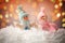 Cute snowmen in snow against blurred Christmas lights on background