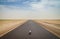 Cute soft toy sitting in middle of empty desert road with diminishing perspective, Mauritania, Africa