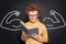 Cute strong little boy reading a book on chalkboard background