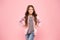 Cute and stylish. Happy baby girl smile on pink background. Brunette girl with long wavy hair in casual autumn style