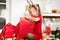 Cute super excited young girl opening large red christmas present while sitting on living room floor. Candid family christmas time