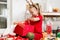 Cute super excited young girl opening large red christmas present while sitting on living room floor. Candid family christmas time