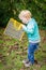 Cute surprised little blond boy looking inside bag outdoor