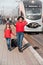 Cute sympathetic beautiful smiling young mother with daughter and suitcase on train background on railway station platform