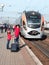 Cute sympathetic beautiful smiling young mother with daughter and suitcase on train background on railway station platform