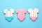 Cute tasty cookies in shape of baby`s onesies on light blue background, flat lay