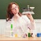 Cute teacher looks at the scales in thought. Scientific research in a school class in a chemistry lesson