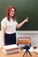 A cute teacher stands in the classroom and writes in chalk on the blackboard. Online education at school and recording video
