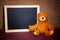 Cute teddybear sitting next to chalkboard