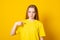 Cute teen girl points at herself, shows mockup space on yellow t shirt, happy being picked