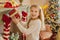 Cute teen girl with present near Christmas tree smiiling