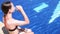 Cute teen girl in swimming suit drinking water at poolside. Healthy lifestyle, summer vacation. Video