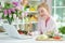 Cute teen girl using laptop while preparing fresh salad on kitchen table