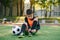 Cute teen soccer player on artificial green covering of outdoors sport field tying the shoelace on boots after training.