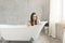 Cute teen woman smiling waiting in the bathtub