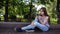 Cute teenage girl checking phone and waiting phone call sitting in park. Video footage HD shooting static camera.