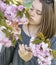 Cute teenage girl inhales the aroma of blooming sakura