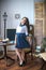 A cute teenage girl with long hair in a classic school dress in a classic interior with books and notebooks at the lesson.