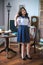 A cute teenage girl with long hair in a classic school dress in a classic interior with books and notebooks at the lesson.