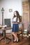 A cute teenage girl with long hair in a classic school dress in a classic interior with books and notebooks at the lesson.