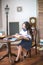 A cute teenage girl with long hair in a classic school dress in a classic interior with books and notebooks at the lesson.