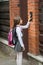 Cute teenage girl ringing in house doorbell after going to school