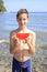 Cute teenager boy holds a slice of watermelon on the beach by the sea