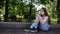 Cute teenager girl checking phone and waiting phone call sitting in park. Video footage HD shooting static camera.