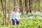 Cute teenager girl on Easter egg hunt in blooming spring garden. Children in snow drop flower meadow. Springtime in the garden