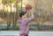 Cute Teenager with orange basketball ball plays basketball on a street playground in spring-summer. Hobby, active lifestyle, sport