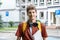 Cute teenager in red shirt, backpack holding a notebook, books in front of his school. Back to school background