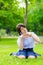 Cute Thai schoolgirl is sitting on the grass and doing heart symbol.