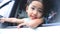 Cute Thailand asian little girl who leaned out of a white car Smiling and waving hello