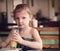 Cute thinking kid girl drinking juice in cafe with serious look