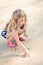 Cute thoughtful little girl with long blond hair squatting