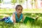 Cute thoughtful little girl lying on a green grass in summer park and holding open book in her hands