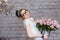 Cute tired young woman holding heavy bucket with pink roses