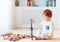 Cute toddler baby boy playing with wooden blocks, building a balancing high tower