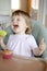 Cute toddler, baby girl in baby chair feeding eating a muffin. Delicious healthy home baked food for kids