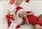 Cute toddler biting xmas ball, lying among present boxes, top view