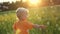 Cute toddler blond boy playing with soap bubbles on summer field. Happy child summertime concept. Authentic lifestyle image