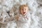 Cute toddler blond boy, playing with white wooden horse in the snow