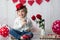 Cute toddler blond child with cute hat, sitting on little sofa with Valentine decoration, isolated background