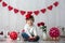 Cute toddler blond child with cute hat, sitting on little sofa with Valentine decoration, isolated background