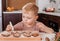 Cute toddler boy decorates Christmas cookies with colorful icing. Seasonal. Boy decorate Christmas cookies for the