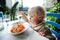 Cute toddler boy eating pasta in indoors restaurant