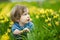 Cute toddler boy having fun between rows of beautiful yellow daffodils blossoming on spring day